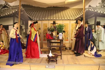 A traditional Korean wedding scene with a couple in colourful robes and a decorated table