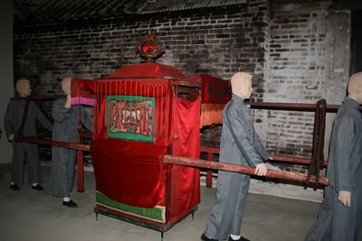 A red wedding sedan chair carried by figures in a museum