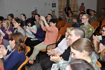 People seated in a hall clapping during a Women's Day gathering