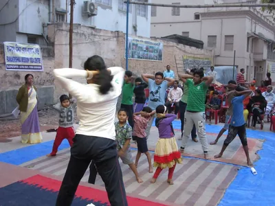 People doing standing stretches on mats in a courtyard