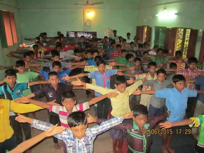 A hall full of students stretching their arms in a yoga class