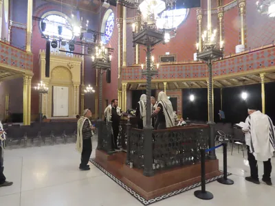 Men in white prayer shawls at the reading platform of a synagogue